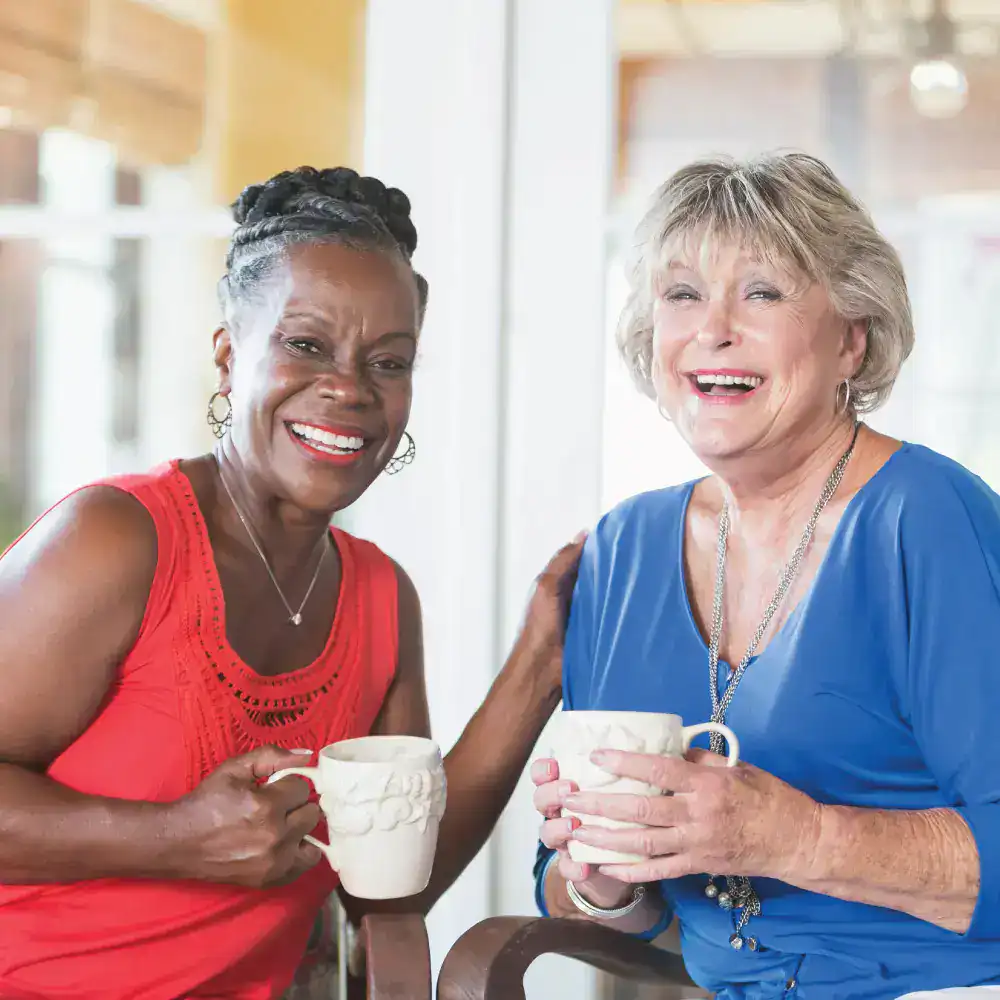 Black senior woman and white senior woman having coffee in a resident's home