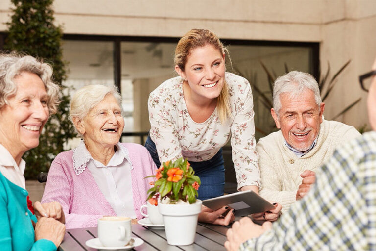 Bellevue | Group of happy senior citizens and staff member sitting at table